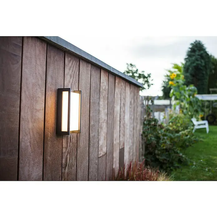 Lutec Aplique exterior LED Qubo - 15 W, 11 x 7,1 x 22 cm, Gris oscuro, IP54 - Aplique moderno de exterior en una pared de madera, emitiendo un brillo cálido y acogedor, acentuando la textura natural de la madera.