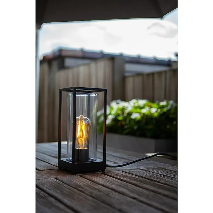 Lutec Lámpara de sobremesa Flair - Altura: 313 mm - Esta moderna lámpara de mesa presenta un marco negro y una carcasa de vidrio con una bombilla brillante y cálida. Está descansando sobre una mesa de madera.