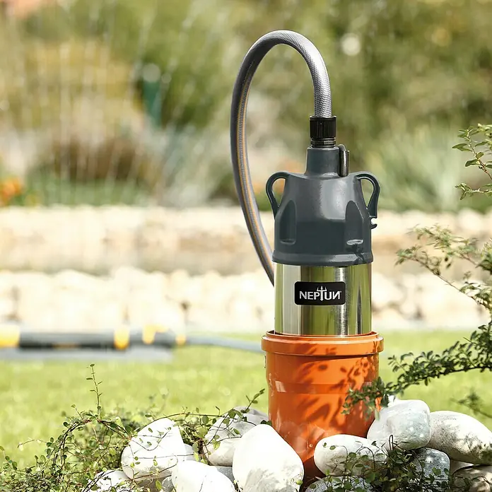 Neptun Drucktauchpumpe NTP-E 80 - 800 W, Max. Fördermenge: 6.000 l/h - NEPTUN Tauchdruckpumpe im Garten, umgeben von Steinen und Grün. Ideal für die Bewässerung und Entwässerung im Außenbereich.