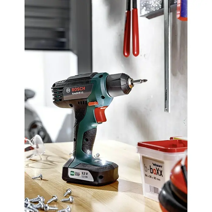 Bosch Power for All 12V Akku-Bohrschrauber EasyDrill 12 - 12 V, 1 Akku, 1,5 Ah, 15 Nm - Nahaufnahme eines Bosch EasyDrill 12 Akku-Bohrschraubers auf einem Tisch mit Schrauben und einer b-boXX.