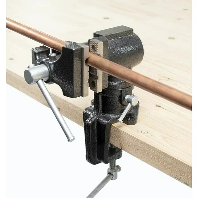 Wisent Multi-Schraubstock - Spannweite: 50 mm, Metall - Rohrbiegevorrichtung mit Kupferrohr auf einer Holzoberfläche. Die Rohrbiegevorrichtung ist schwarz und das Kupferrohr ist braun.