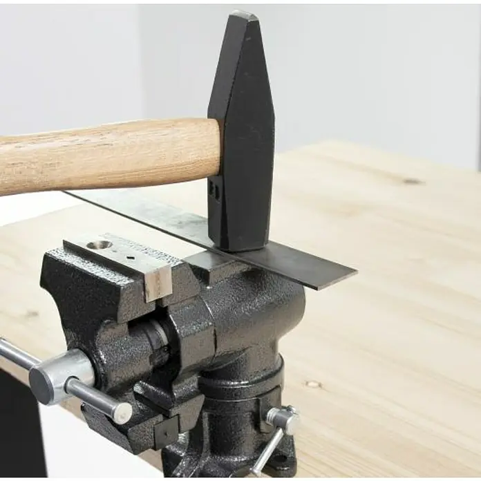 Wisent Multi-Schraubstock - Spannweite: 50 mm, Metall - Bild einer Schraubstock mit einem Hammer, der ein Stück Metall bearbeitet, das im Schraubstock befestigt ist.