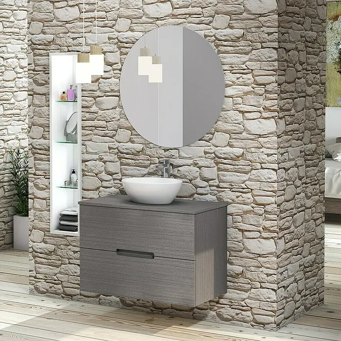 Artysan Conjunto de mueble de baño Loop Top - Ancho: 80 cm, 4 pzs., Ceniza, Mate - Un tocador de baño moderno con un gabinete gris, espejo redondo y lavabo sobre encimera blanco contra una pared de piedra.