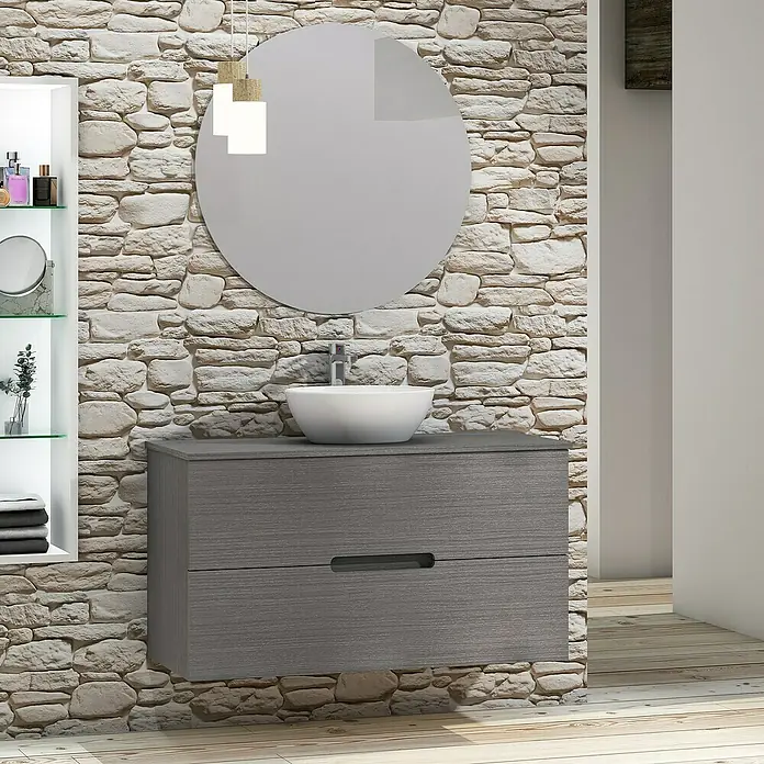 Artysan Conjunto de mueble de baño Loop Top - Ancho: 100 cm, 4 pzs., Ceniza, Mate - Mueble de baño con gabinete gris, lavabo sobre encimera y espejo redondo frente a una pared de piedra.