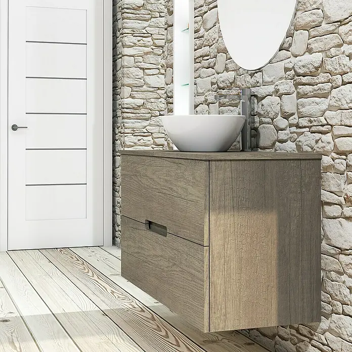 Artysan Conjunto de mueble de baño Loop Top - Ancho: 100 cm, 4 pzs., Nebraska, Mate - Lavabo de baño moderno con mueble de madera y espejo redondo frente a una pared de piedra, junto a una puerta blanca.