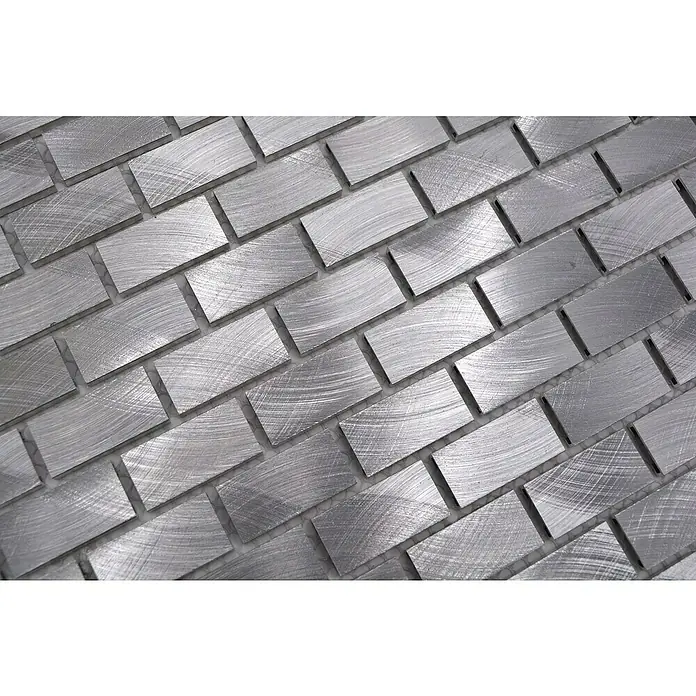 Mosaikfliese Brick XAM A411 - 30,6 x 32,4 cm, Silber, Matt - Nahaufnahme eines Musters aus gebürsteten Edelstahlfliesen, die in einem Fischgrätenmuster angeordnet sind und eine moderne Textur zeigen.