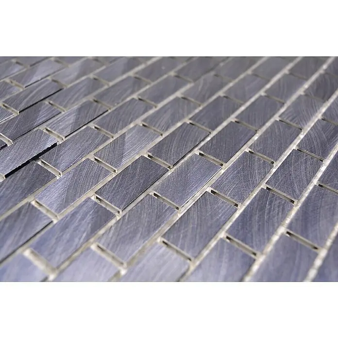 Mosaikfliese Brick 3D Mix XAM A421 - 30,6 x 32,4 cm, Schwarz, Matt - Nahaufnahme von rechteckigen, silberfarbenen Metallfliesen mit gebürsteter Textur, verlegt in einem Fischgrätmuster für eine moderne Optik.