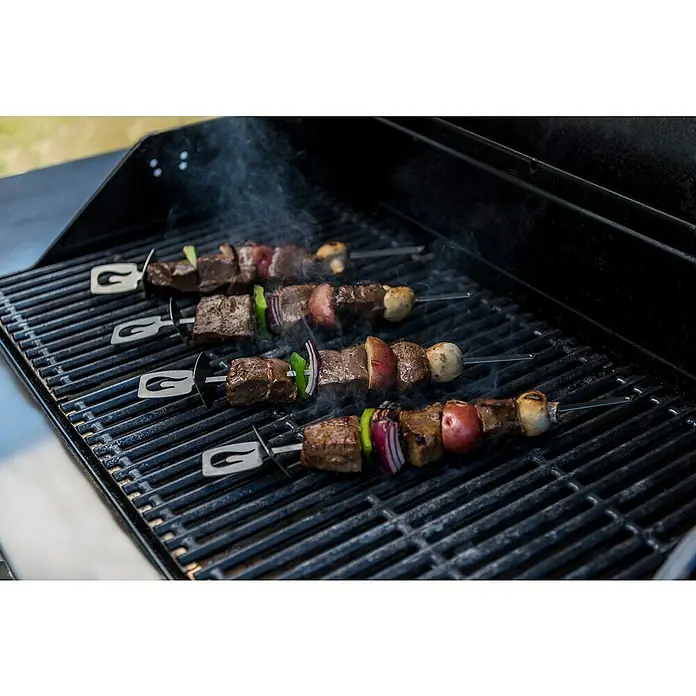 Char-Broil Grillspieß Grill+ - Länge: 35 cm, 4 -tlg. - Nahaufnahme von vier Grillspießen mit Fleisch, Paprika, Zwiebeln, Kartoffeln und Champignons auf einem Grillrost, Rauch steigt auf.