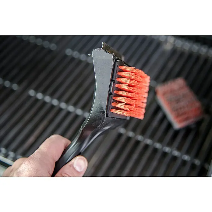 Char-Broil Ersatzbürstenkopf - Passend für: Char-Broil Grillbürste Cool-Clean Premium, Textil - Nahaufnahme einer Grillbürste mit roten Borsten und schwarzem Griff über einem Grillrost. Ideal für die Reinigung von Grillrückständen.