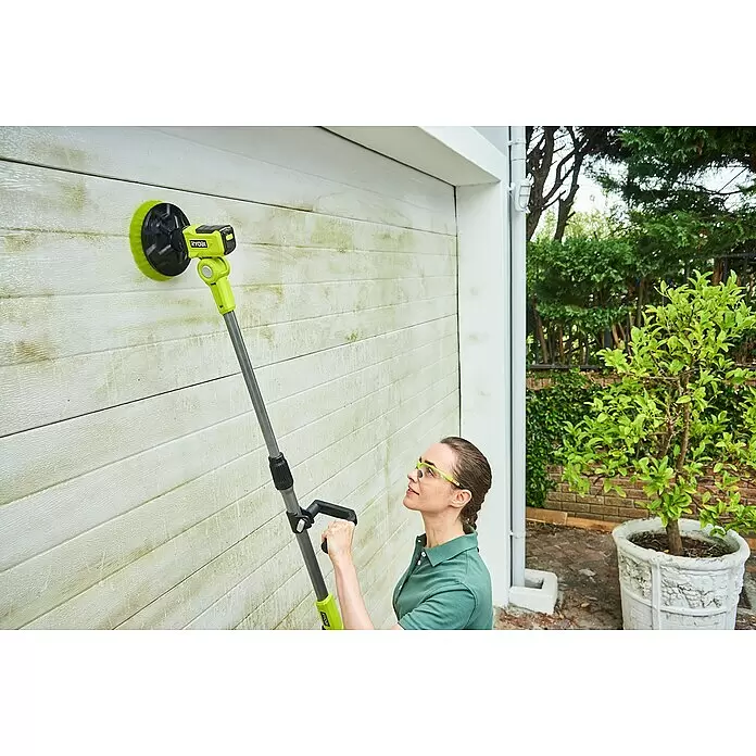 Ryobi ONE+ Cepillo rotativo de lavado R18TPS‐120G - 18 V, Iones de litio, 2 Ah - Mujer usa un cepillo eléctrico Ryobi verde lima y negro con mango extensible para limpiar una pared blanca sucia.