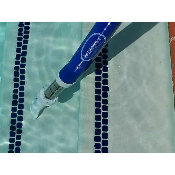 Zodiac Aspirador para piscina Spa Wand - Manual - Primer plano de un limpiafondos azul Polaris SpaWand bajo el agua, aspirando los residuos entre las baldosas de la piscina.