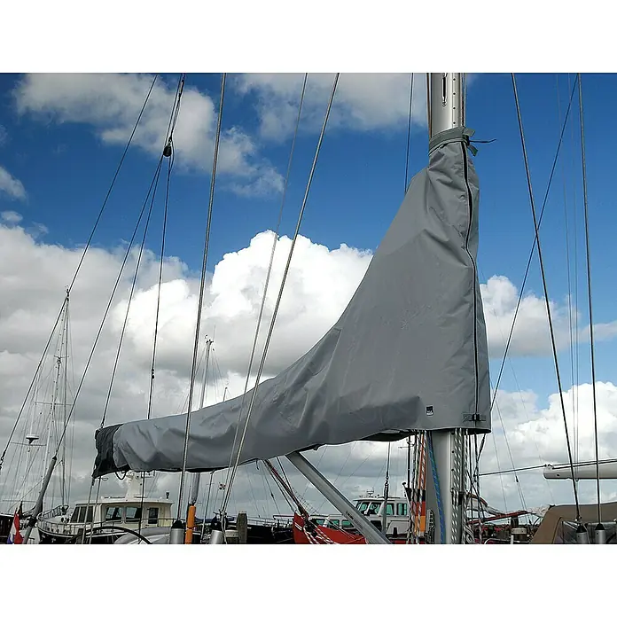 Blue Performance Segel-Schutzhülle - L x H: 410 x 137 cm, Geeignet für: Großsegel - Das Bild zeigt ein Segelboot mit einem grauen Segelkleid am Mast vor einem Himmel mit weißen Wolken. Das Segelkleid schützt das Segel vor Witterungseinflüssen.