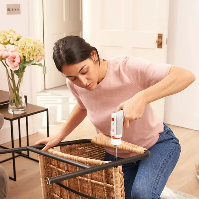 Black+Decker Atornillador de batería HEXDRIVER - 3,6 V, 1 batería, 1,5 Ah, 5,5 Nm - Una mujer monta una silla de mimbre con un destornillador inalámbrico, centrándose en la precisión.