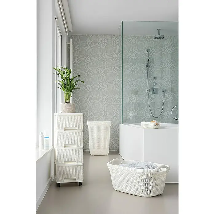Curver Knit Cesta para la ropa - 57 l, Blanco, Plástico - Escena de baño con cesto para la ropa blanca, cómoda con cajones y planta, creando un ambiente elegante y funcional.
