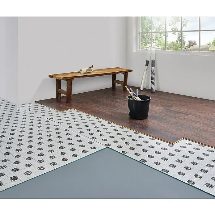 LOGOCLIC Dämmunterlage Maxima Aquastop Smart - 5,55 m², Stärke: 5 mm - Aufbau eines dunklen Laminatbodens mit Trittschalldämmung in einem hellen Raum. Werkzeuge und eine Bank stehen bereit für die Fertigstellung.