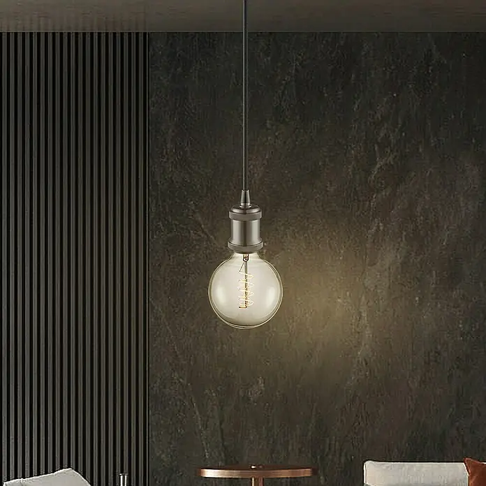 Home Sweet Home Lampenfassung Perle - E27, Farbe: Schwarz, Metall - Nahaufnahme einer einzelnen hängenden Edison-Glühbirne, die ein warmes Licht in einem modern eingerichteten Raum ausstrahlt.