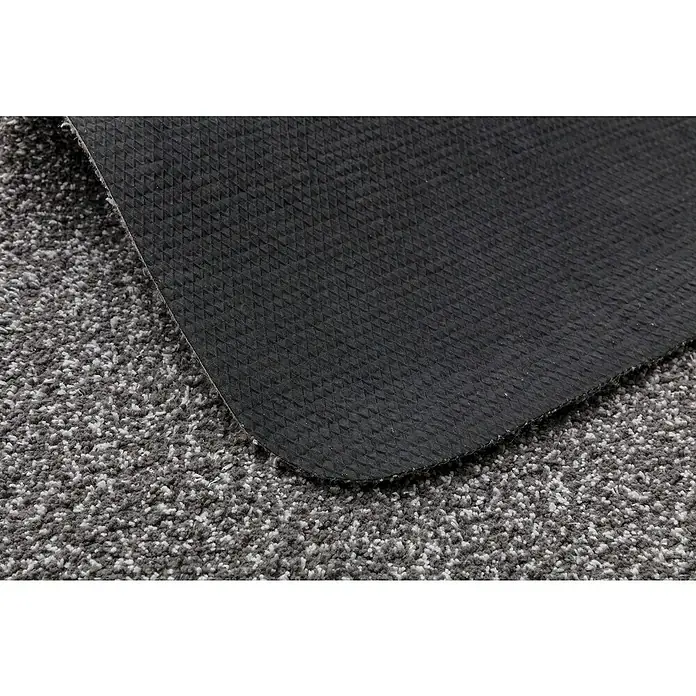 Astra Schmutzfangmatte entra SAUGSTARK - Dunkelgrau, 75 x 130 cm, Material Nutzschicht: 100 % Baumwolle - Nahaufnahme einer schwarzen Fußmatte mit rutschfester Unterseite, die auf einem grauen Teppich liegt, ideal für den Innenbereich.