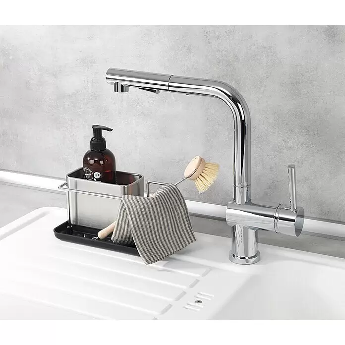 Wenko Spülbecken-Organizer - L x B x H: 12 x 21 x 10,5 cm - Ein Spülbecken-Organizer aus Edelstahl mit braunem Seifenspender, gestreiftem Tuch und Spülbürste, neben einem Chromwasserhahn in einem weißen Spülbecken.