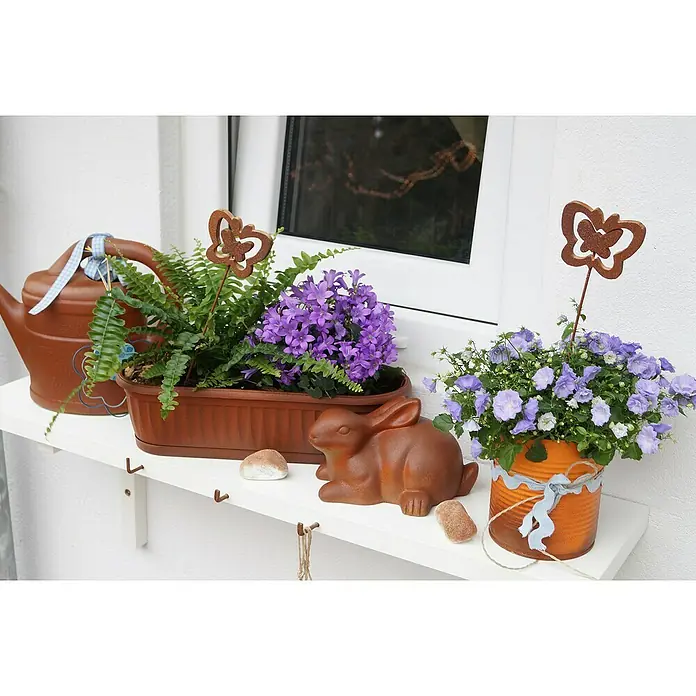 Dupli-Color Effect Spezial-Lackspray Rust Effect - Rostbraun, Matt, 400 ml - Eine Fensterbank mit lila Glockenblumen in Töpfen, einer Gießkanne und einem Schokoladenhasen, die eine gemütliche und festliche Dekoration ergibt.