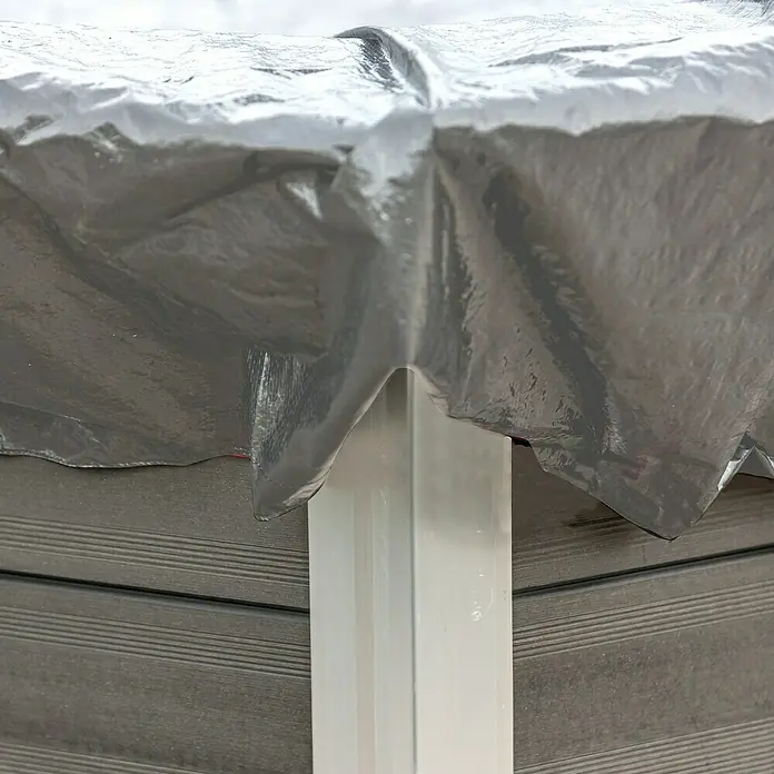 Gre Pool-Abdeckplane Winter - 580 g/m², Durchmesser: 440 cm, Kunststoff - Graue Plane, die über ein weißes, rechteckiges Rohr und eine graue, holzähnliche Oberfläche gelegt ist. Schützt die darunter liegende Struktur.