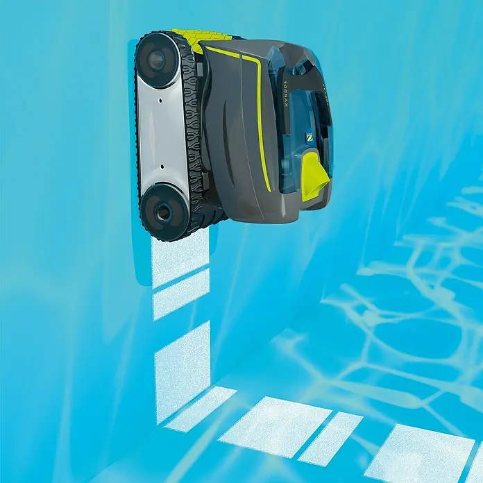 Zodiac Poolroboter Tornax GT 3220 - Netzbetrieben, Passend für: Pools bis 900 x 400 cm, Filterleistung: 11 m³/h - Das Bild zeigt einen Tornax Poolreinigungsroboter, der an einer blau gefliesten Poolwand befestigt ist und die Reinigungsleistung hervorhebt.