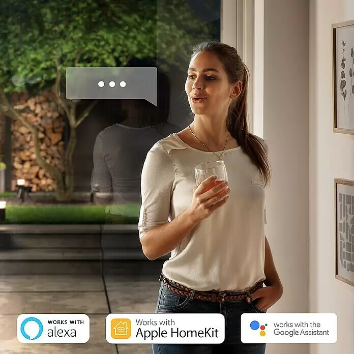 Philips Hue LED-Außenwandleuchte Appear - 8 W, 11,7 x 8,4 x 24 cm, Schwarz, IP44 - Frau interagiert mit einem Smart-Home-System, dargestellt durch eine Sprechblase und Logos für Alexa, Apple HomeKit, Google Assistant.