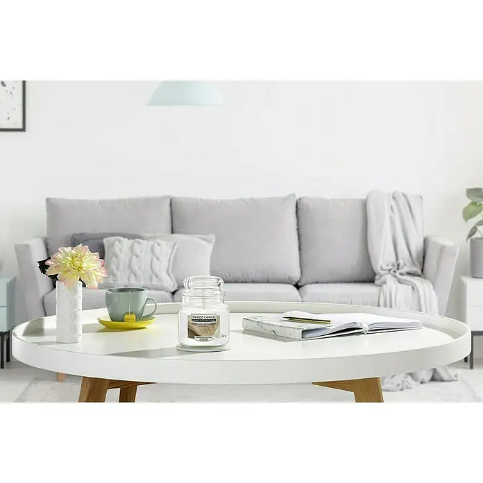 Yankee Candle Home Inspirations Duftkerze - Im Glas, White Linen & Lace, Medium - Nahaufnahme einer Yankee Candle auf einem Tisch, die eine gemütliche und entspannende Atmosphäre verspricht. Sanfte Beleuchtung betont das Dufterlebnis.