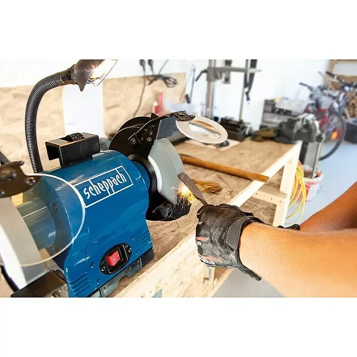 Scheppach Elektro-Doppelschleifer BG 200 - 550 W, Durchmesser Trockenschleifscheibe: 200 mm - Blaue Scheppach Schleifmaschine in Gebrauch, schärft einen Meißel mit Funken, eine behandschuhte Hand hält das Werkzeug.