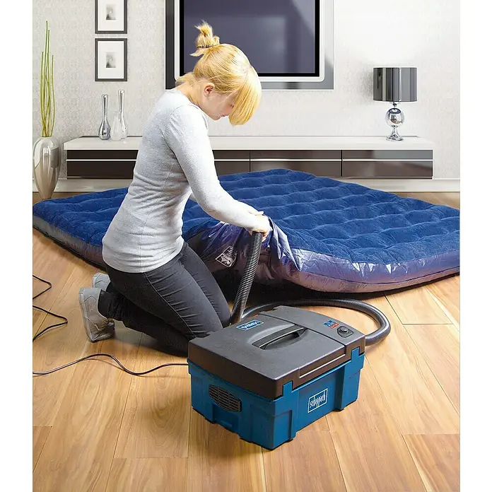 Scheppach Absauganlage HD2P - Max. Luftleistung: 120 m³/h, Füllmenge: 5 l, 1.250 W - Frau pumpt Luftmatratze mit einer Scheppach Luftpumpe auf. Das Gerät ist blau-schwarz und steht auf einem Holzboden.