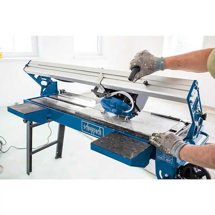 Scheppach Elektro-Fliesenschneider FS3600 - 900 W, Max. Schnittlänge: 920 mm, Schnitttiefe bei 90 °: 36 mm - Eine Scheppach Fliesenschneidmaschine wird benutzt, um Fliesen zu schneiden. Die Maschine ist blau und silber und hat einen Arbeitstisch.