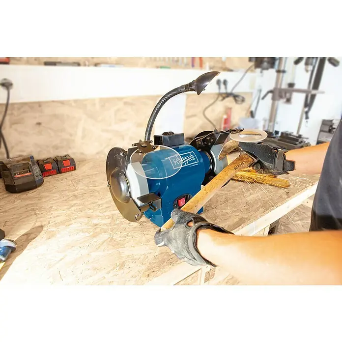 Scheppach Elektro-Doppelschleifer BG 150 - 370 W, Durchmesser Trockenschleifscheibe: 150 mm - Schleifmaschine beim Schärfen eines Hammers, mit Schutzvorrichtungen und Lampe für präzises Arbeiten.