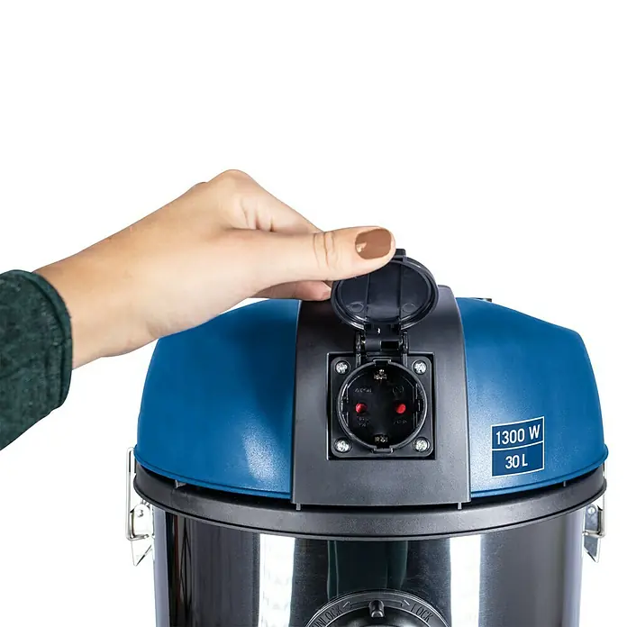 Scheppach Aspirador en seco y húmedo eléctrico NTS30 - 1.300 W, 30 l - Una mano abre la tapa de un enchufe en una aspiradora azul de 30L y 1300W.
