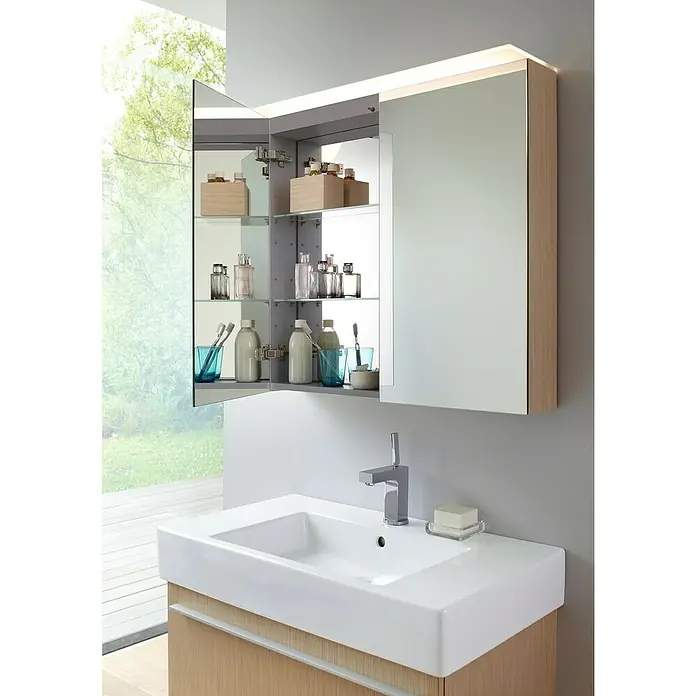 Duravit Vero Waschtisch - 85 x 49 cm, Ohne Spezialglasur, Hahnloch: Mitte, Mit Überlauf, Weiß, Ungeschliffen - Ein modernes Badezimmer mit einem beleuchteten Spiegelschrank, einem weißen Waschbecken und Armaturen. Der Schrank ist teilweise geöffnet.