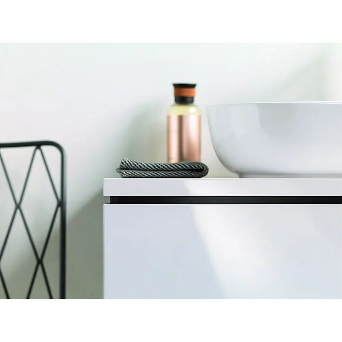 Duravit Luv Aufsatzwaschbecken - 80 x 40 cm, Ohne Spezialglasur, Hahnloch: Ohne, Ohne Überlauf, Weiß - Nahaufnahme eines weißen Waschbeckens mit einer Flasche und einem Handtuch auf einem weißen Unterschrank, akzentuiert durch ein schwarzes Gestell.