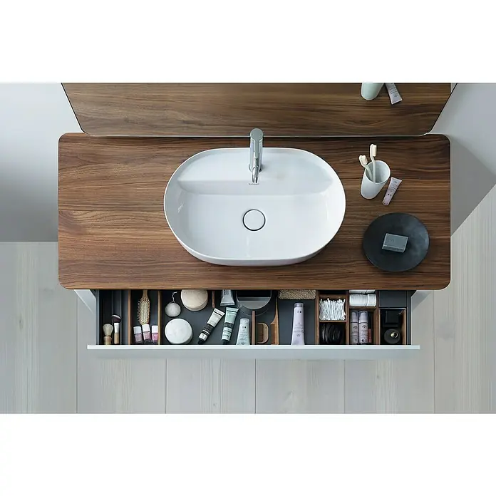 Duravit Luv Aufsatzwaschbecken - 80 x 40 cm, Ohne Spezialglasur, Hahnloch: Mitte, Ohne Überlauf, Weiß Seidenmatt - Ansicht von oben auf ein modernes Waschbecken mit Holzplatte und einer offenen Schublade, die mit verschiedenen Toilettenartikeln gefüllt ist.