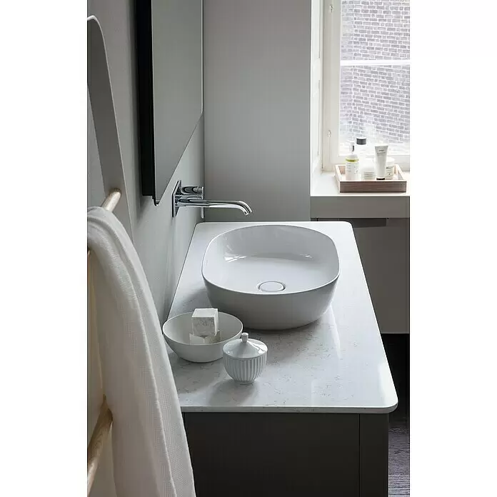 Duravit Luv Aufsatzwaschbecken - 60 x 40 cm, Ohne Spezialglasur, Hahnloch: Ohne, Ohne Überlauf, Weiß - Weißes Aufsatzwaschbecken, verchromter Wandhahn und helle Arbeitsplatte auf einem dunkelgrauen Badunterschrank.