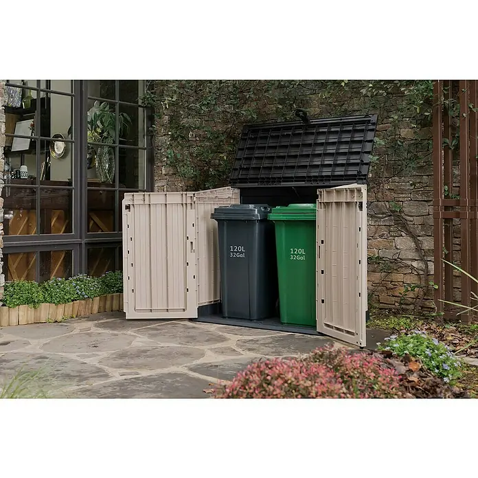 Keter Arcón Store It Out Midi - L x An x Al: 71,5 x 132 x 113,5 cm, Beige/Marrón, Plástico - Esta toma presenta un cobertizo doble de plástico beige y negro para contenedores con ruedas, que contiene dos contenedores. Está situado en un patio.