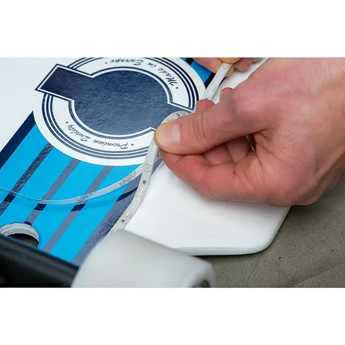 Paulmann LED-Band Function Mobil Strip - Länge: 0,8 m, Lichtfarbe: RGB - Eine LED-Leiste wird an einem Skateboard mit blau-weißem Design befestigt, die das Produkt hervorhebt.