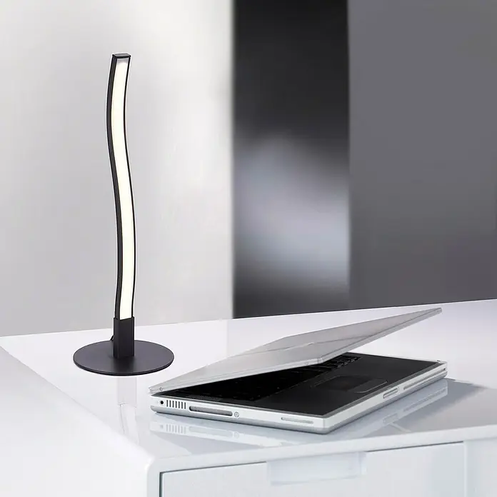 Just Light LED-Tischleuchte Wave - 3 W - Elegante LED-Tischleuchte in Schwarz neben einem Laptop auf einem weißen Tisch. Ideal für moderne Arbeitsbereiche.