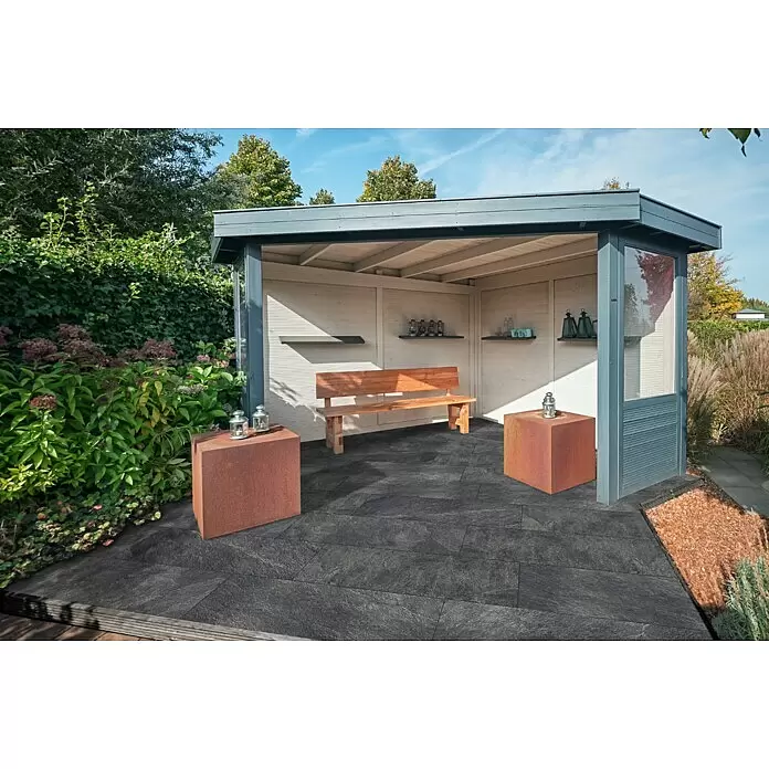 Terrassenfliese Cera 2.0 - 40 x 120 x 2 cm, Museo Ardesia Nero, Matt - Dunkelgraue Terrassenplatten bedecken den Boden einer modernen Outdoor-Pergola mit Holzbank und rustikalen Metallwürfeln.