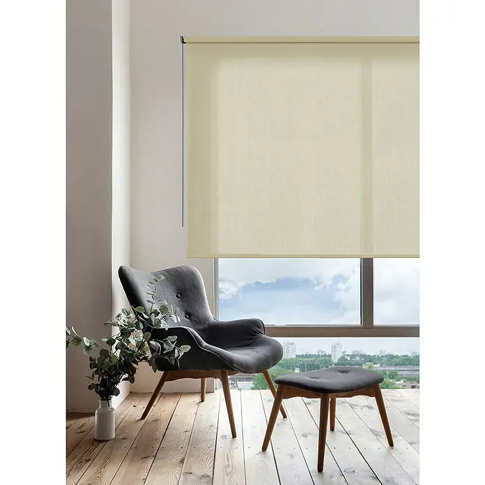 Estor enrollable Soft - An x Al: 200 x 250 cm, Beige - Acogedor rincón de lectura con un sillón gris, un reposapiés a juego y persianas enrollables beige que proporcionan una luz suave y difusa para un espacio relajado.