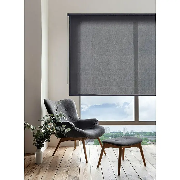 Estor enrollable Soft - An x Al: 200 x 250 cm, Marengo - Un estor enrollable gris delante de una ventana con una silla y un taburete delante. Proporciona privacidad y luz suave a la habitación.