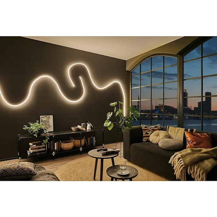 Paulmann MaxLED LED-Band Flow Basisset - Länge: 1,5 m - Wohnzimmer mit stilvoller Wandleuchte, dunkler Einrichtung und Fenster mit Stadtblick.