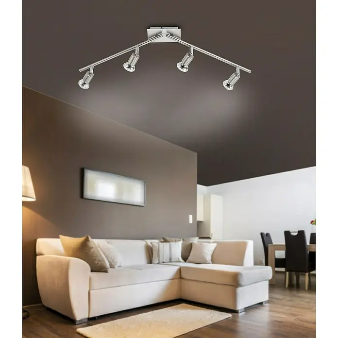 Tween Light Estima LED-Wandstrahler - 12 W, L x B x H: 80 x 74 x 16 cm, Stahl, Warmweiß, 4 Stk. - Deckenleuchte mit vier Strahlern aus Metall, die einen modernen Wohnraum mit braunen Wänden und einer weißen Couch beleuchten.
