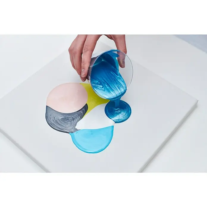 Liquitex Professional Gießmedium Irisierend - 473 ml, Transparent - Ein Kunstwerk entsteht: Blaue Farbe wird auf eine Leinwand mit bereits vorhandenen Farbklecksen gegossen.
