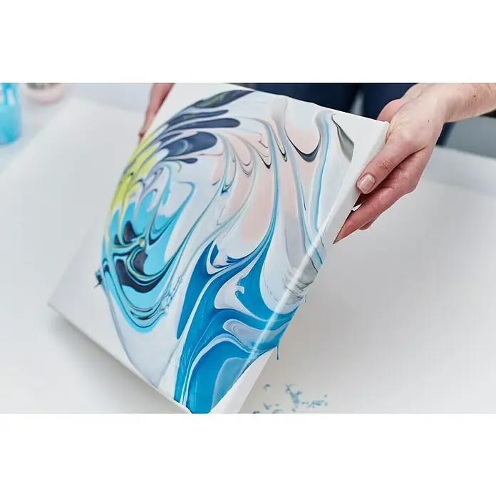 Liquitex Professional Gießmedium Irisierend - 473 ml, Transparent - Nahaufnahme eines bemalten Kunstleinwandes mit blau-weißem Farbmuster, das von einer Person gehalten wird.
