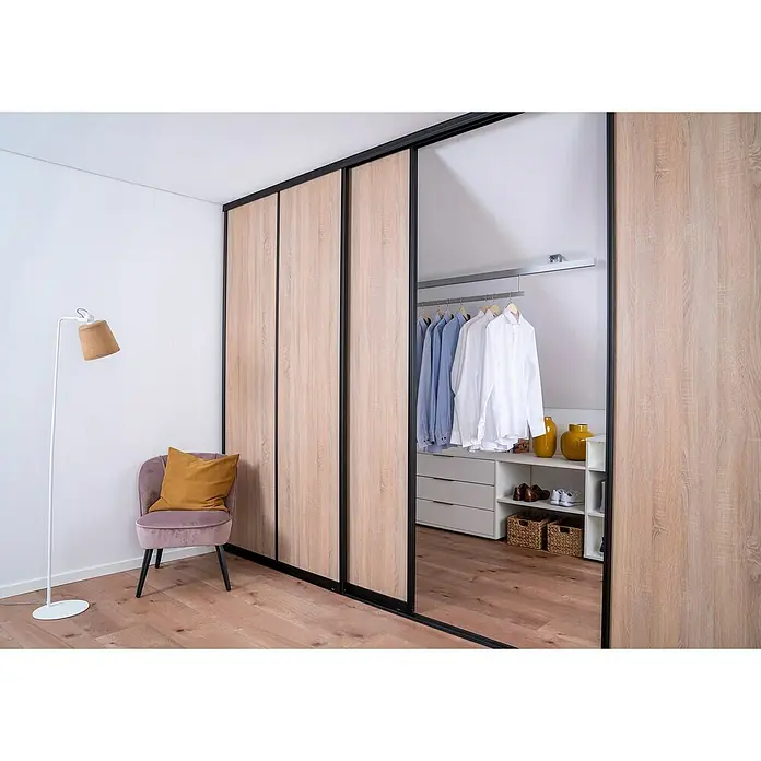 Room Plaza Easy Schiebetür-Bau-Set - Eiche geplankt/Eiche Trüffel, Farbe Beschlag: Schwarz - Innenansicht eines Schranks mit Schiebetüren in hellem Holzton und schwarzem Rahmen, der Stauraum und Kleidung präsentiert.
