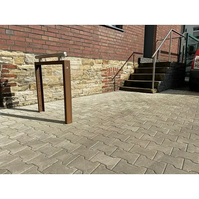 Schake Fahrrad-Anlehnbügel - B x H: 80 x 110 cm, Passend für: 2 Fahrräder, Beidseitige Radeinstellung - Eine moderne Fahrradstanderanlage aus Metall steht vor einer Ziegelmauer, die Fahrräder sicher und stilvoll parkt.