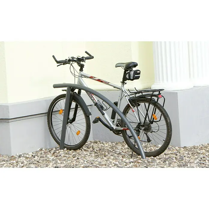 Schake Fahrrad-Anlehnbügel - B x H: 140 x 114 cm, Passend für: 2 Fahrräder, Beidseitige Radeinstellung, Dunkelgrau - Ein silbernes Mountainbike ist an einem Fahrradständer aus Metall vor einem Gebäude abgestellt, der eine sichere Aufbewahrung gewährleistet.