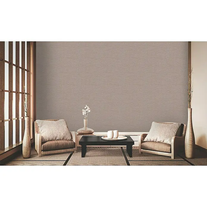 A.S. Création Metropolitan Stories II Vliestapete Uniquer - Braun/Gold, Uni, 10,05 x 0,53 m - Ein ruhiger Wohnraum mit zwei Sesseln, einem schwarzen Tisch und natürlichen Elementen für eine entspannte Atmosphäre.